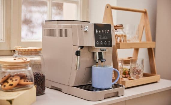 Kaffeemaschine auf Küchenarbeitsplatte neben Keksglas und blauem Kaffeebecher.