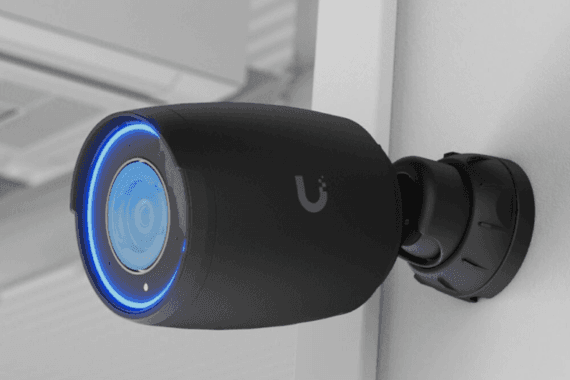 Schwarze Überwachungskamera mit blau leuchtendem Ring, seitlich an einer Wand montiert