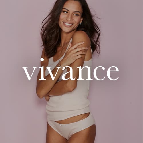 vivance – Frau in weißem Tanktop und Slip steht vor rosa Hintergrund