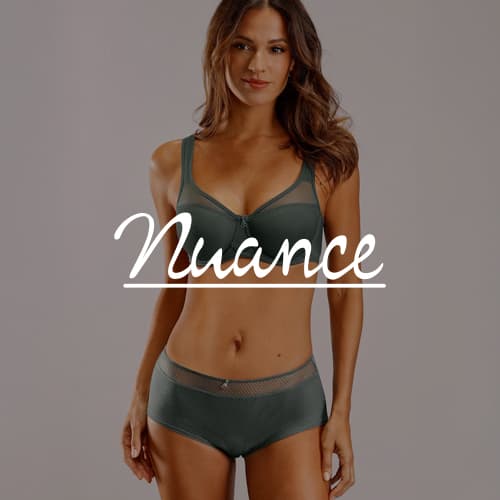 Nuance – Frau in grünem BH und Panties posiert vor grauem Hintergrund