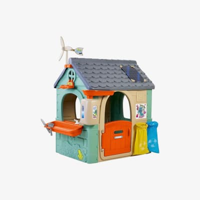 Spielhaus für Kinder mit grauem Dach, orangener Tür, Windrad, Solarpanel, Müllsäcken und Fenster mit Blumenkasten