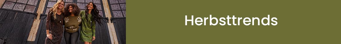 Herbsttrends – Drei Frauen in herbstlichen Outfits lehnen sich vor einer dunklen Tür zusammen