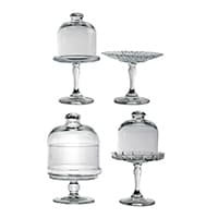 Vier verschiedene Glas-Tortenständer, zwei mit Hauben und zwei ohne Hauben, auf weißem Hintergrund.