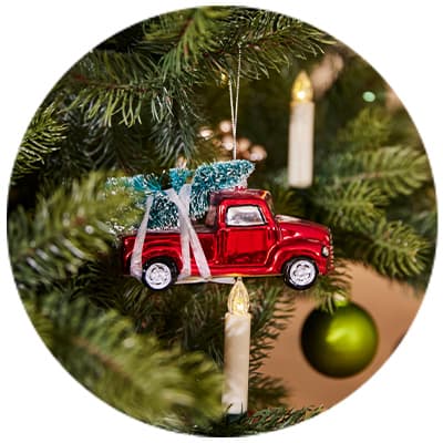 Rot glänzender Weihnachtsbaumanhänger in Form eines Trucks mit Tannenbaum auf einem grünen Tannenbaum dekoriert
