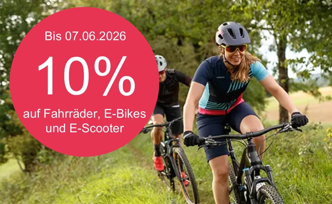 Bis 07.06.2026 10 % auf Fahrräder, E-Bikes und E-Scooter – zwei Personen fahren mit Helmen auf Mountainbikes durch Grünfläche