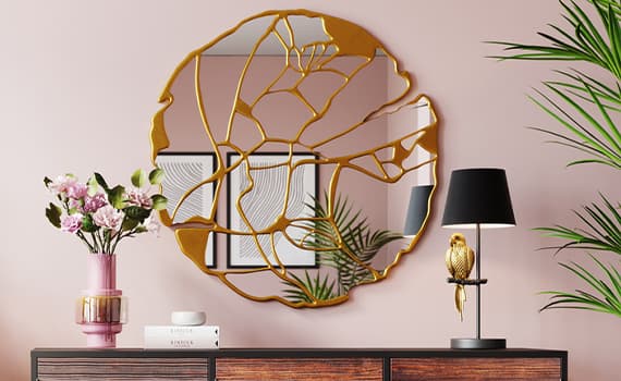 Runder Spiegel mit goldenen Details über einer Kommode, auf der eine Vase mit Blumen, Bücher und eine Lampe stehen