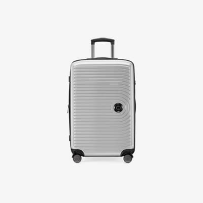 Silberner Rollkoffer mit geriffelter Oberfläche und schwarzem Griff, steht auf vier Rädern.
